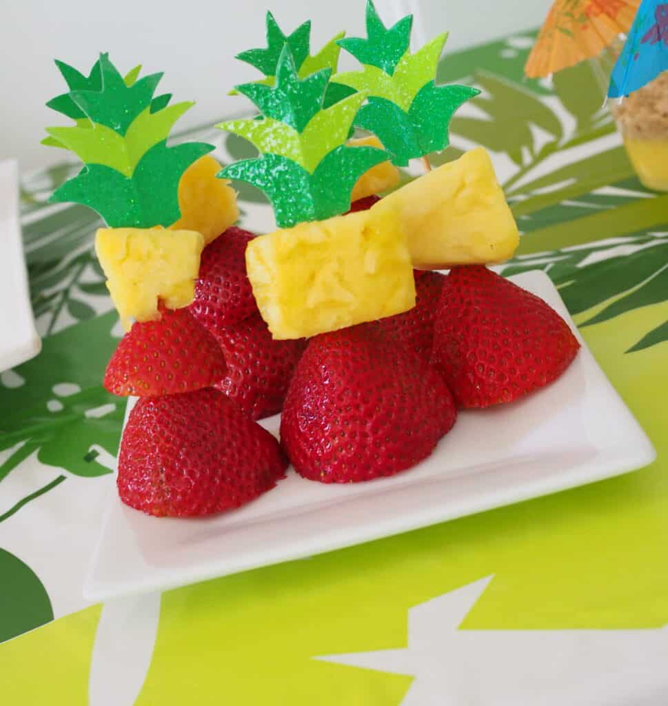 Easy Luau Ideas For Kids party foods. Paper leaf topper on pineapple and strawberries