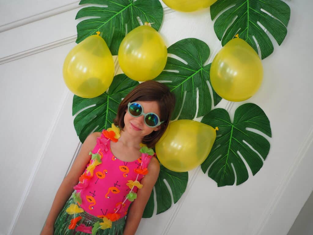 Easy Luau ideas for kids party decor. Using balloons and leaves as a photo background